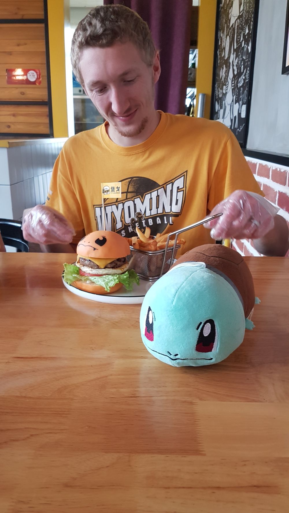 Me in a casual restaurant with a Squirtle plushie and a burger that looks like a Charmander
